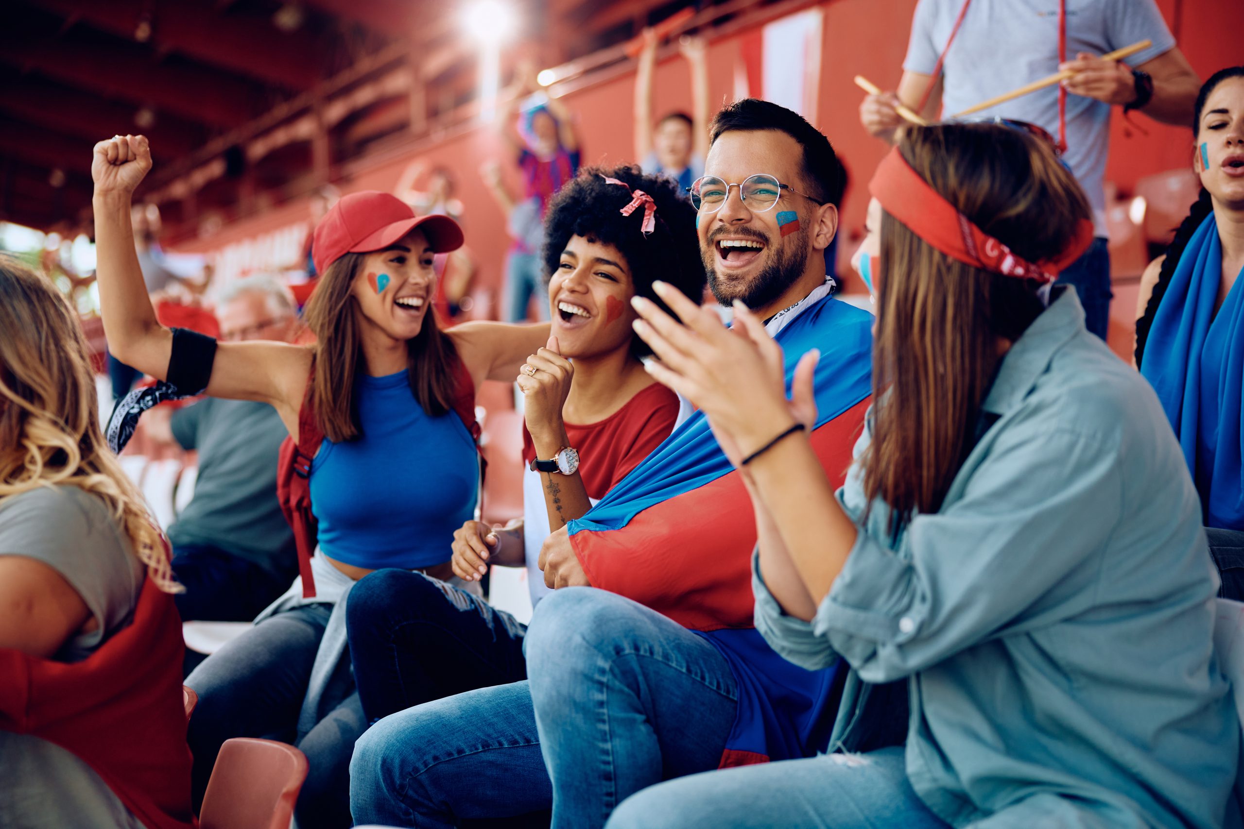 group of sports fans having fun while cheering during the match at the stadium.